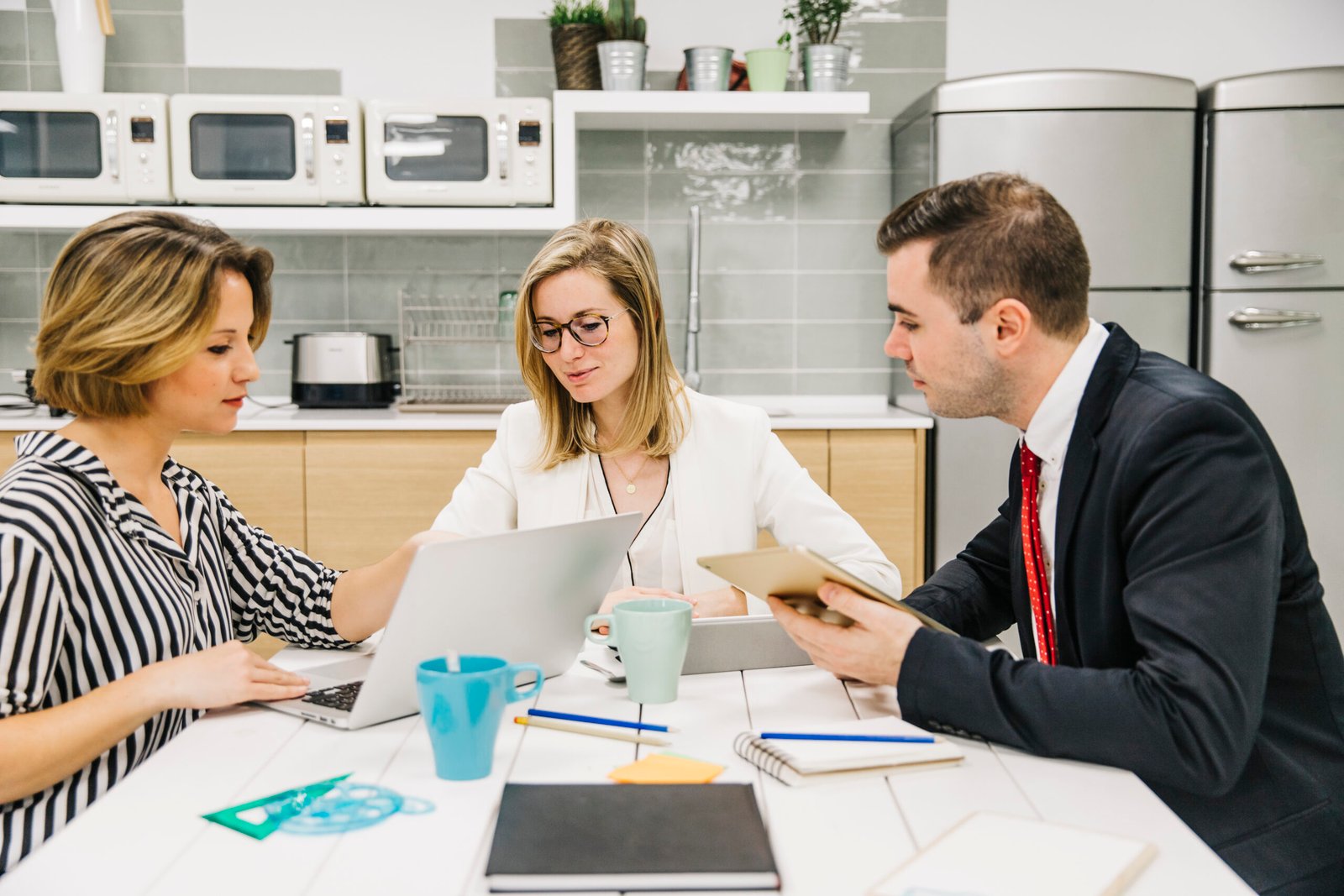 Real estate lawyer meeting with clients in a modern office , reviewing documents and contracts on a laptop and tablet during a collaborative discussion