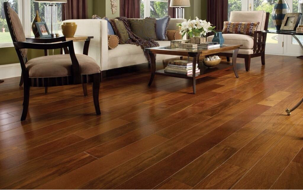 A stylish living room featuring rich, dark hardwood flooring with a comfortable seating area, showcasing elegant furniture and natural lighting.
